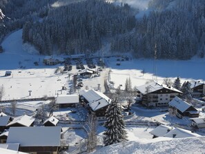 Un pueblo cubierto de nieve con edificios, un estacionamiento y una pista de esquí.