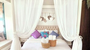 A four-poster canopy bed with a tufted headboard, multiple pillows, and a basket of towels. - Beyaz Kapı Boutique Hotel (Cesme)