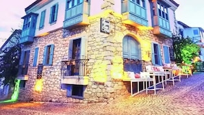 A stone building with a balcony, a sign, and a staircase leading up to it. - Beyaz Kapı Boutique Hotel (Cesme)