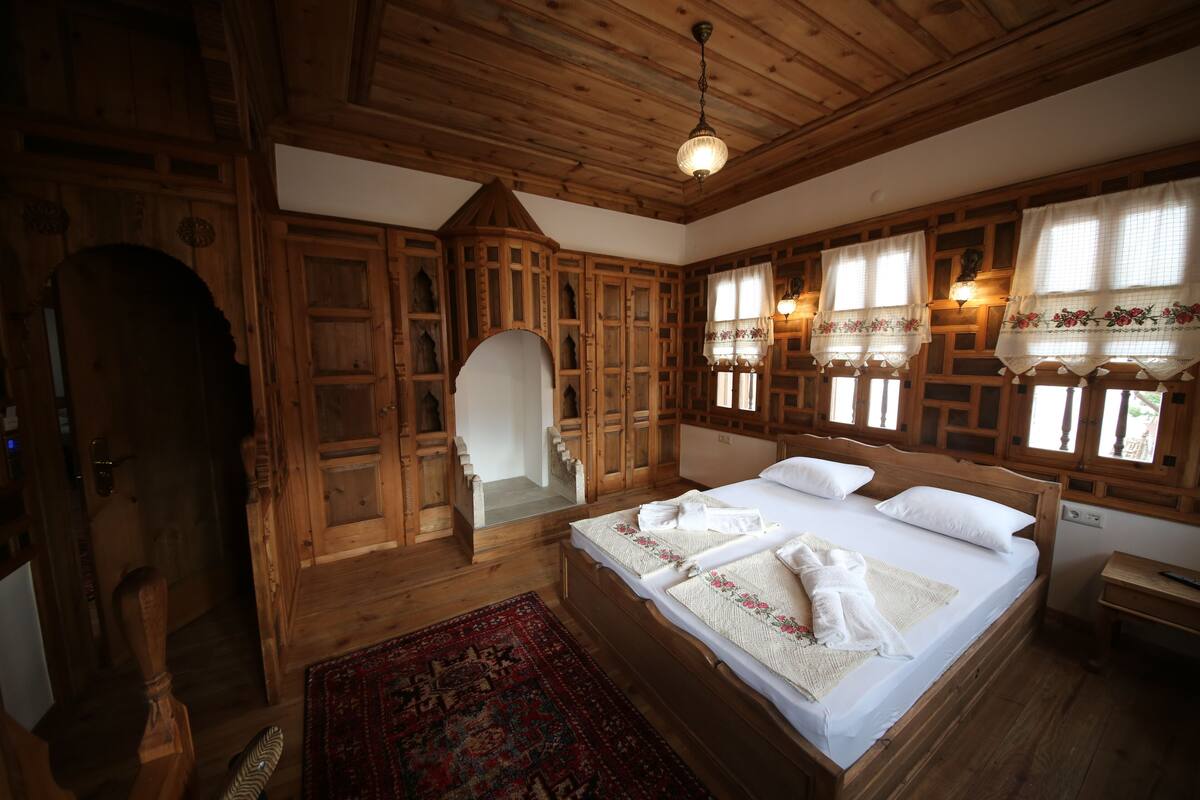Een slaapkamer in chaletstijl met een groot bed, een houten garderobe en een klein bureau.