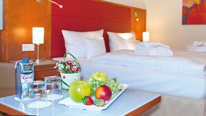 A hotel room with a bed, bedside tables, and a fruit plate. - Morada Hotel Heidesee Gifhorn (Gifhorn)