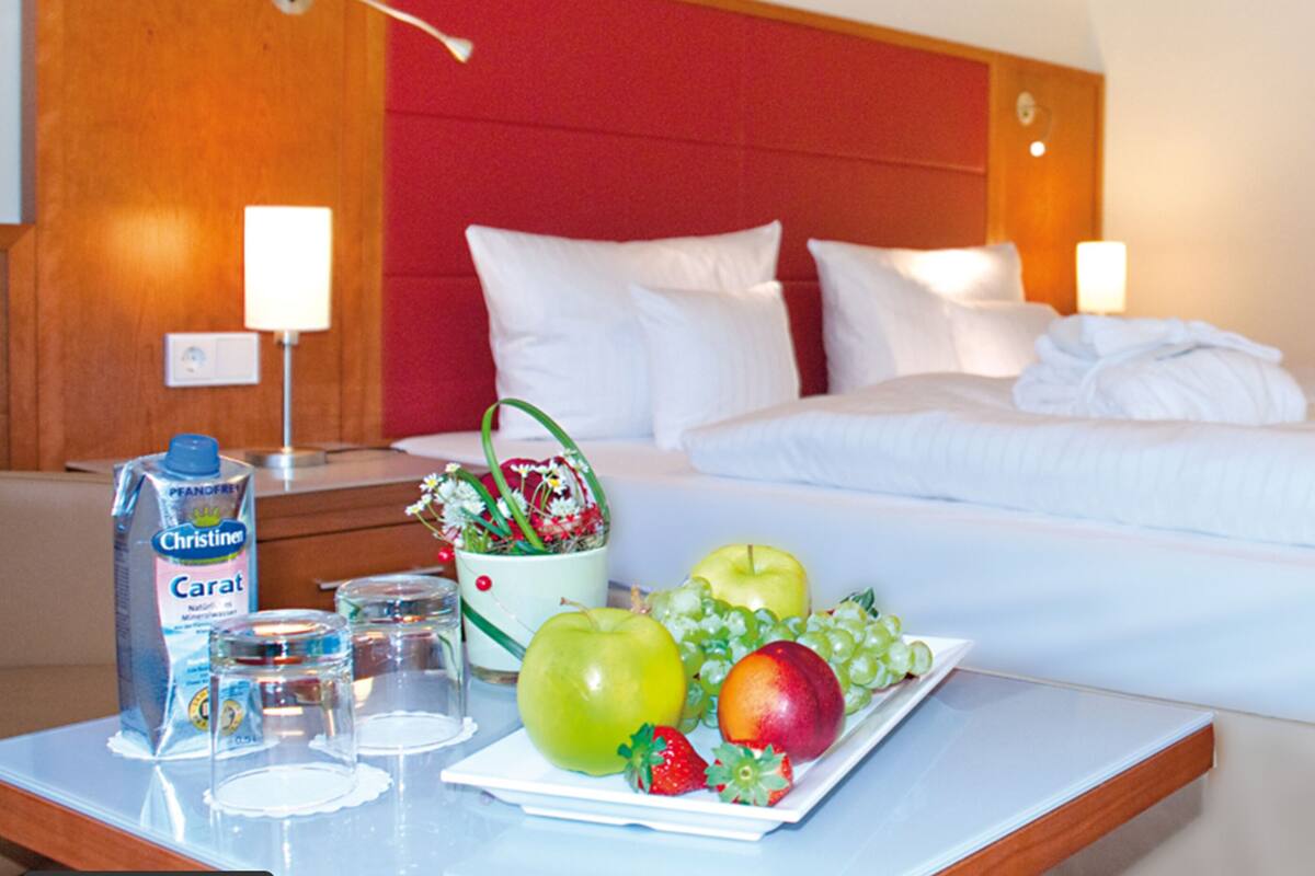 A hotel room with a bed, bedside tables, and a fruit plate.