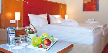 Una habitación de hotel con una cama, mesitas de noche y una bandeja de frutas.