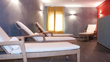A spa area with wicker lounge chairs, a small table, and a wall-mounted light fixture.