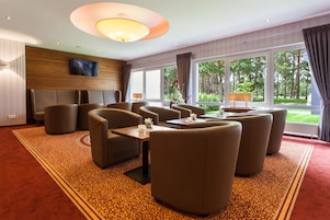Habitación de hotel con un ventanal grande, televisor de pantalla plana y zona de estar con sofás y una mesa.