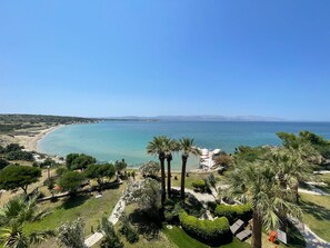 A coastal resort with a clear view of the sea, palm trees, and a well-maintained garden. - Babaylon Hotel (Cesme)