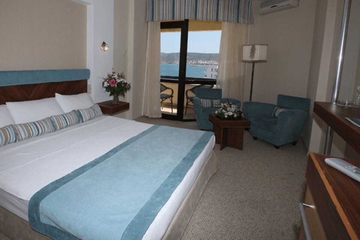 Une chambre d’hôtel avec un grand lit, un balcon avec vue, un bureau et une chaise.