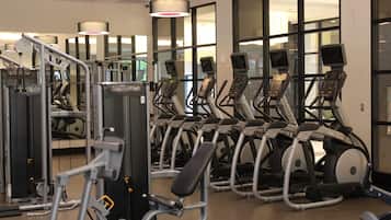 Een fitnessruimte met meerdere loopbanden, krachtapparaten en trainingsmaterialen.