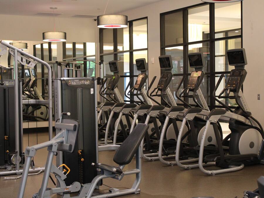 Een fitnessruimte met meerdere loopbanden, krachtapparaten en trainingsmaterialen.
