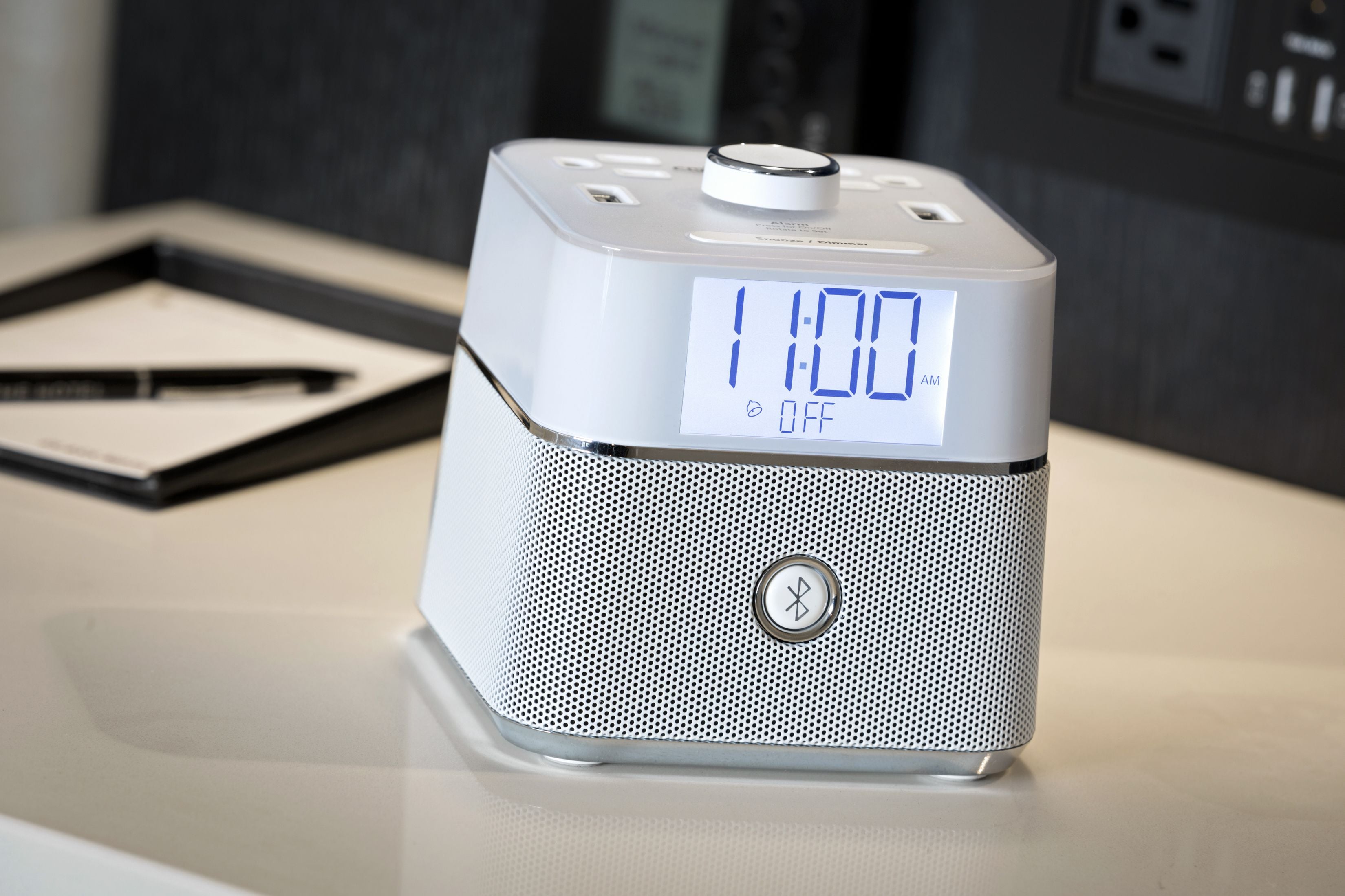 A modern alarm clock with a digital display on a table.