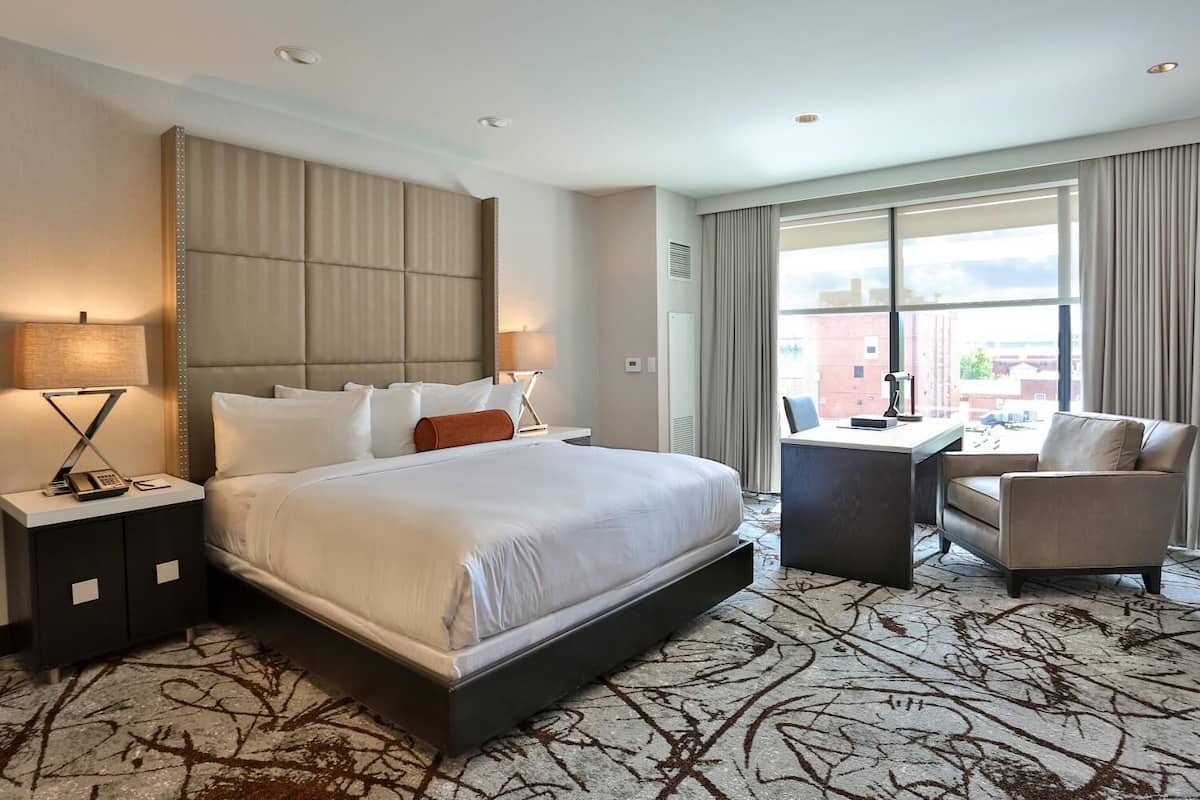 A modern hotel room with a large bed, a desk, and a chair.