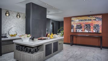 Una cocina moderna con una isla central, muebles oscuros y un cuadro abstracto grande en la pared.