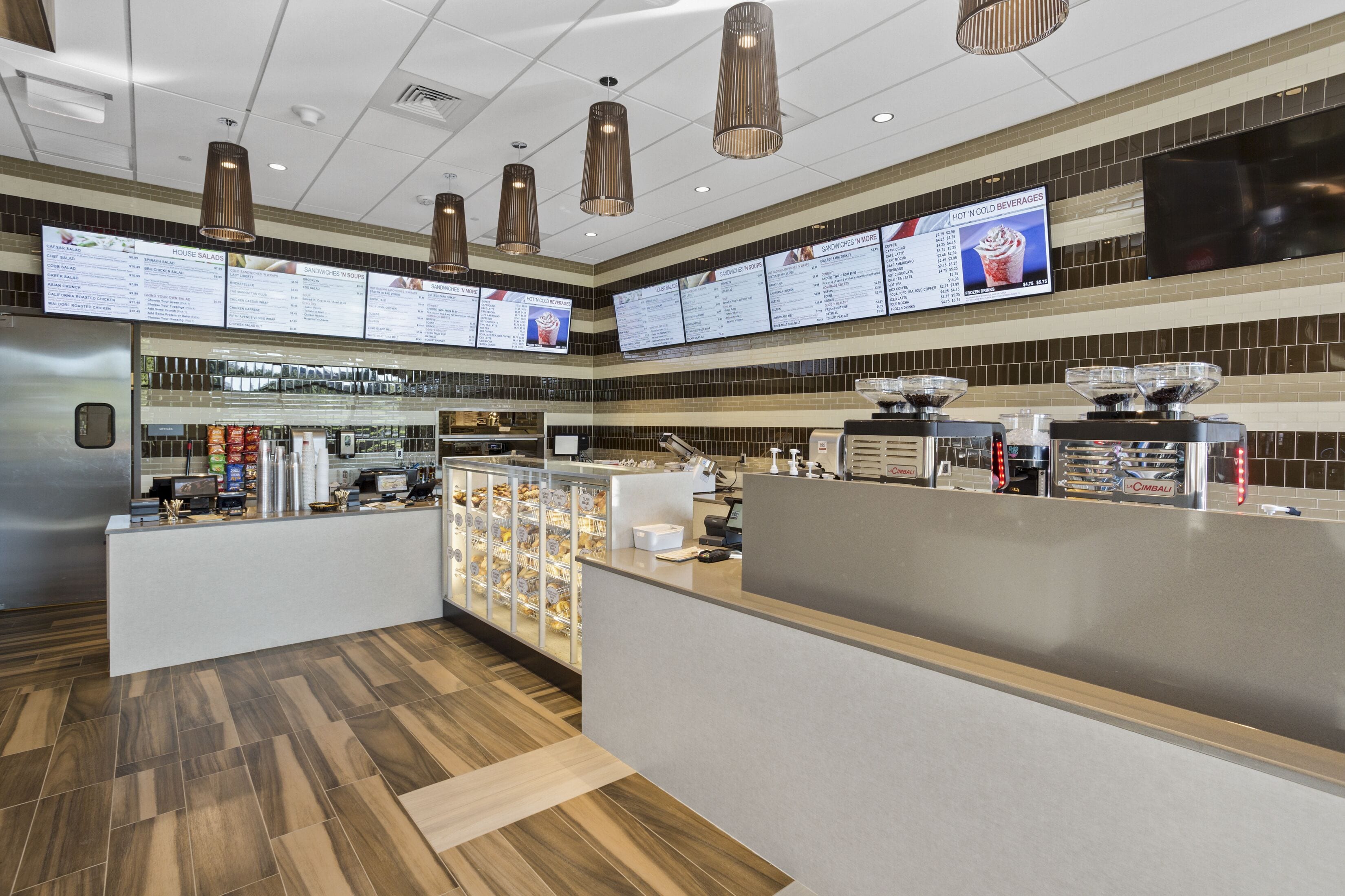 A modern restaurant interior with a central counter, menu boards, and a coffee station.