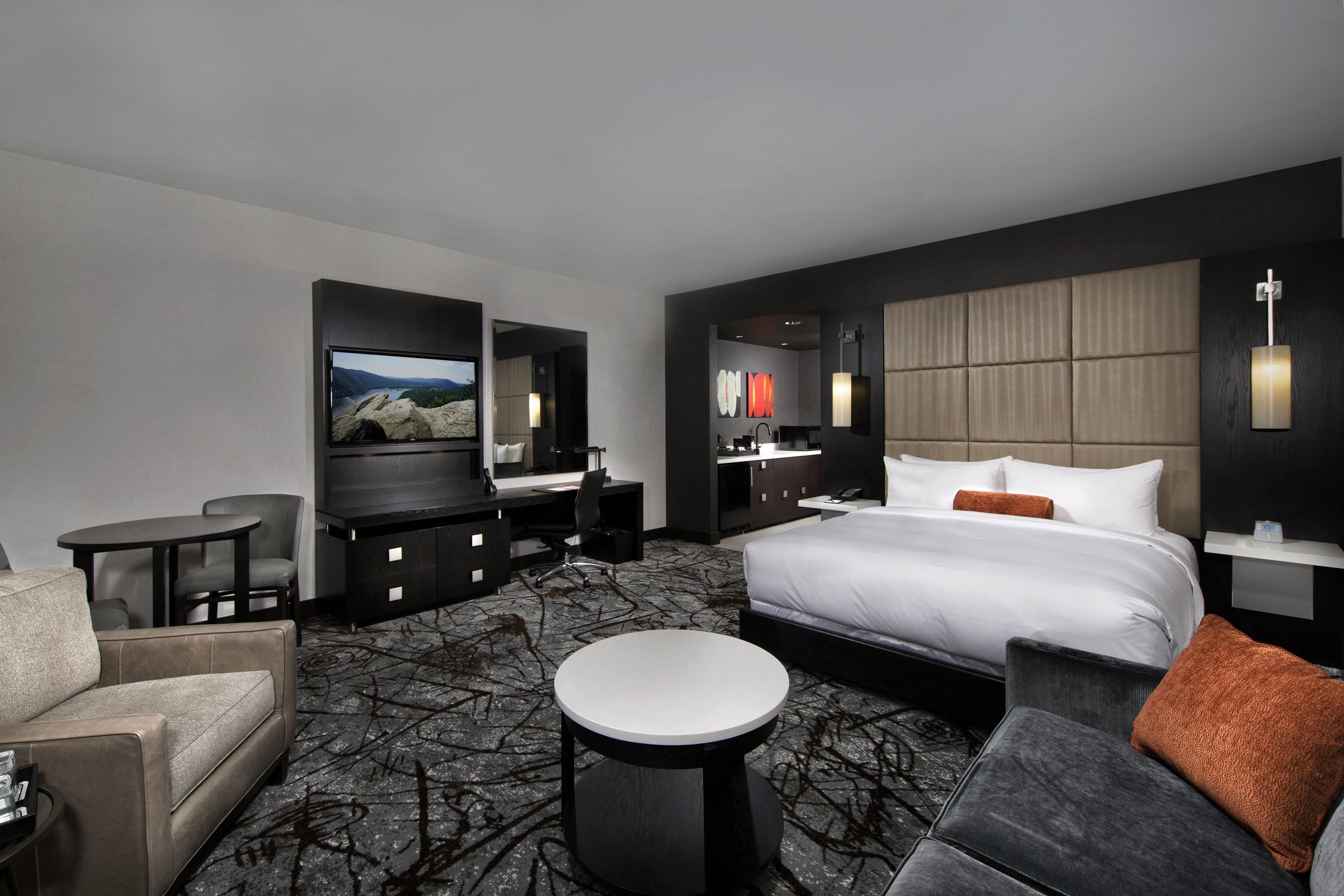 Una habitación de hotel moderna con una cama grande, un escritorio, un televisor y una zona de estar.