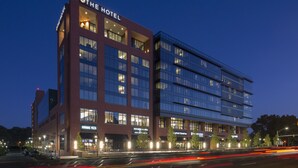 Un moderno edificio de hotel con varios pisos, grandes ventanales y un cartel llamativo que dice "THE HOTEL".