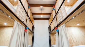 A corridor with bunk beds, wooden walls, and a ceiling light.