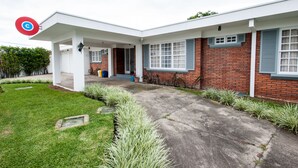 A modern two-story house with a covered patio, a brick exterior, and a well-maintained lawn. - Capital Hostel de Ciudad (San José)