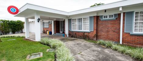 A modern two-story house with a covered patio, a brick exterior, and a well-maintained lawn.