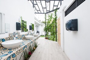 A modern bathroom with a large white sink, a patterned tile backsplash, and a small garden area with a pergola. - Capital Hostel de Ciudad (San José)