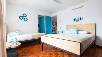 Un dormitorio con dos camas, piso de madera y una puerta azul.