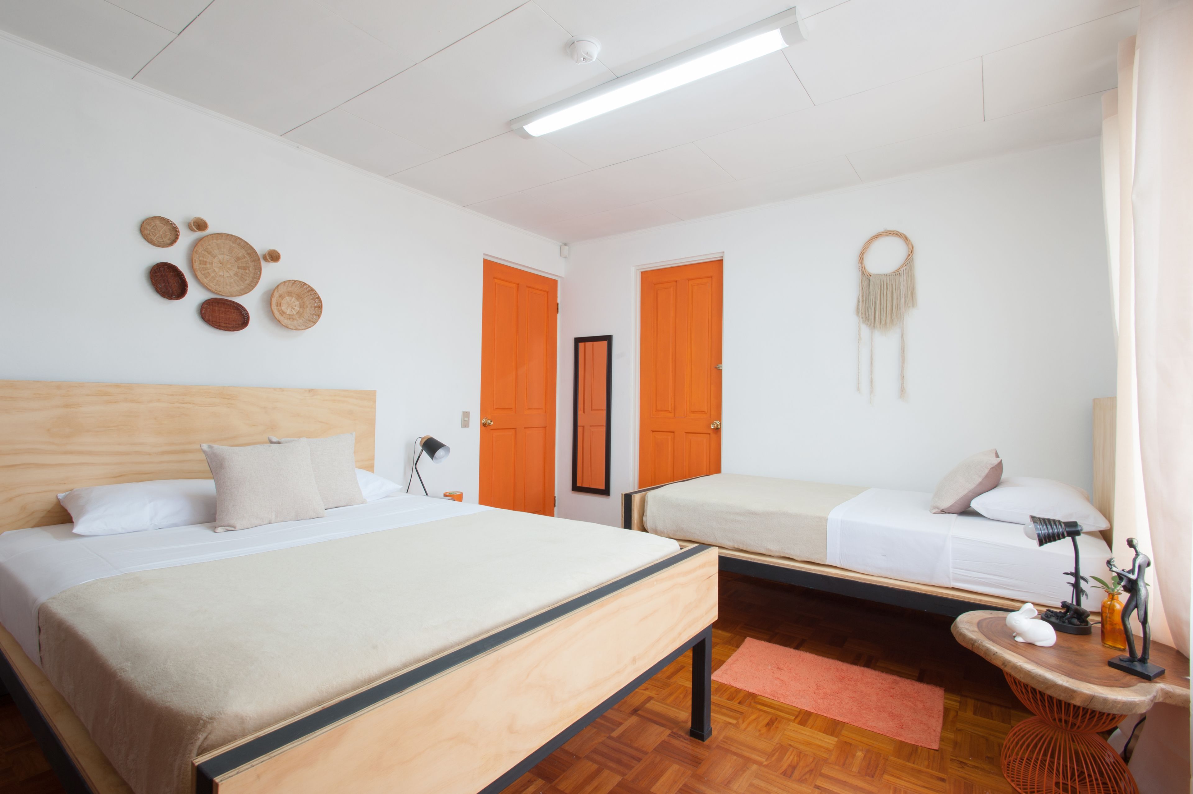 Une chambre avec deux lits, une tête de lit en bois, un miroir et un mur décoré d’assiettes.