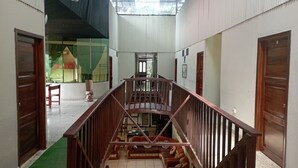 A spacious interior with a central staircase, wooden railings, and a tiled floor. - Grand Selva Lodge & Tours (Ahuano)