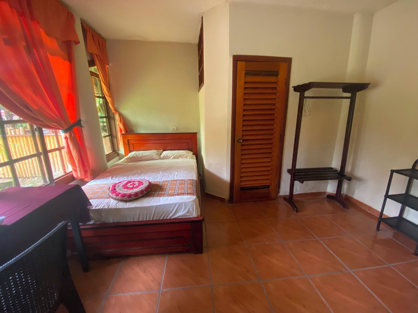 Un dormitorio con cama, una puerta de madera, una silla y una mesita.