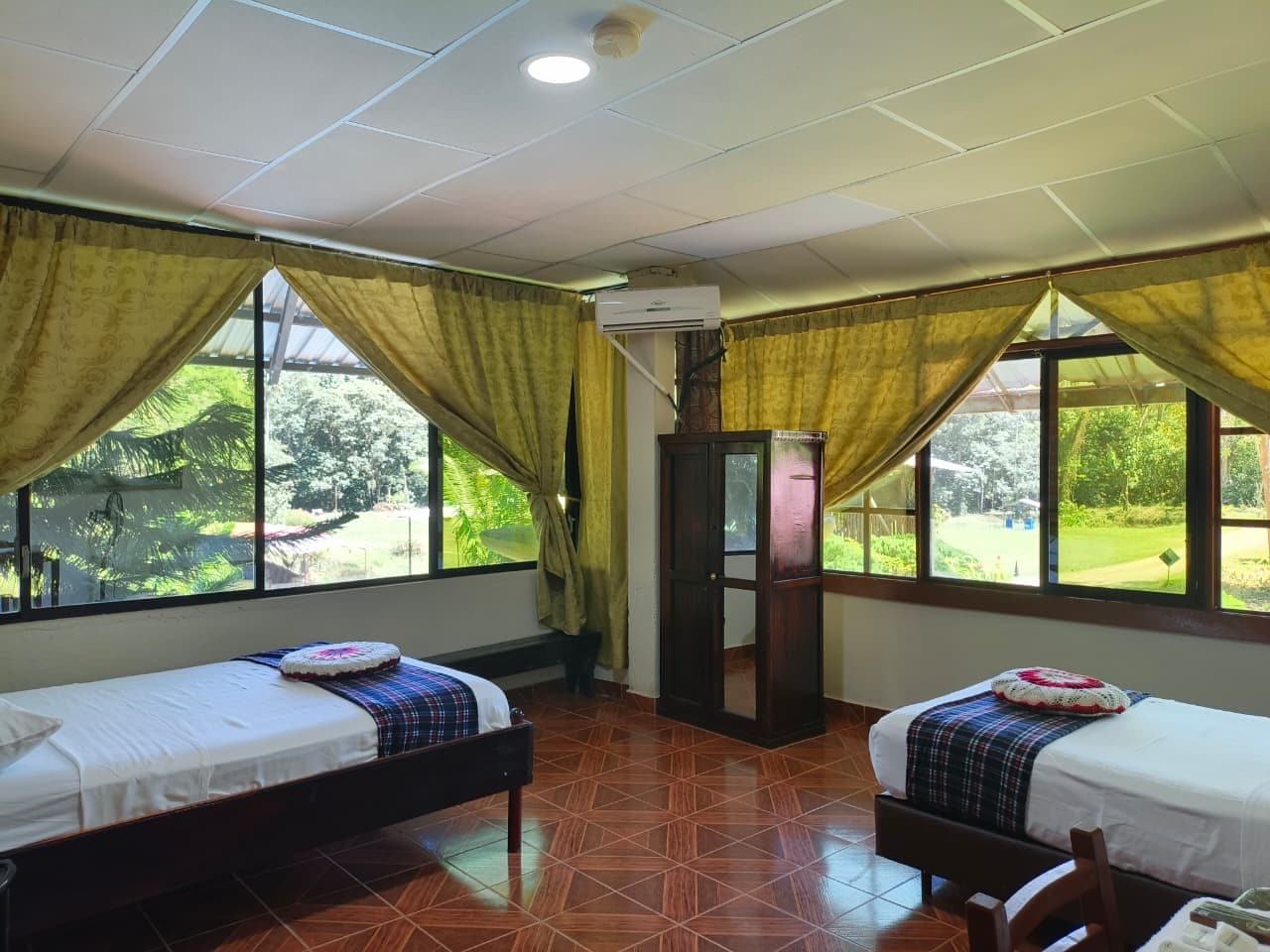 A room with two beds, a wardrobe, and a window with curtains.