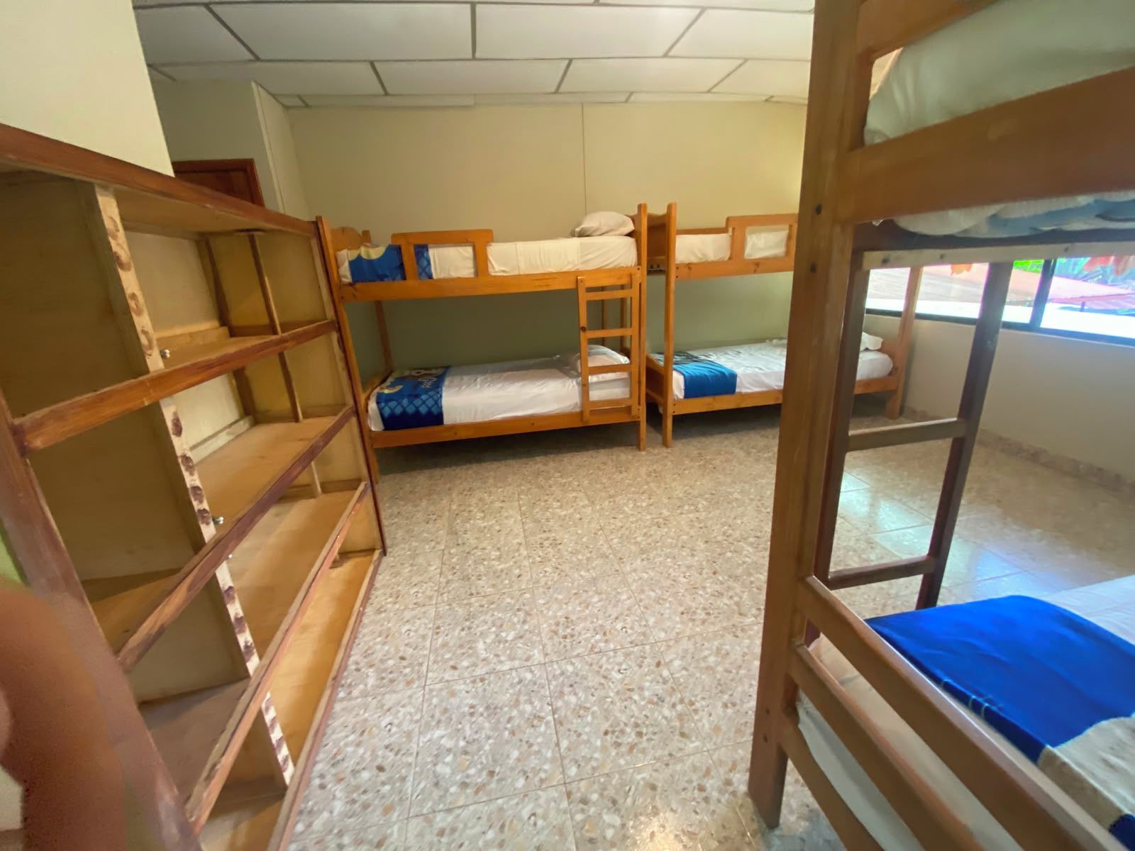 Un dormitorio con literas, una escalera de madera y suelo de baldosas.