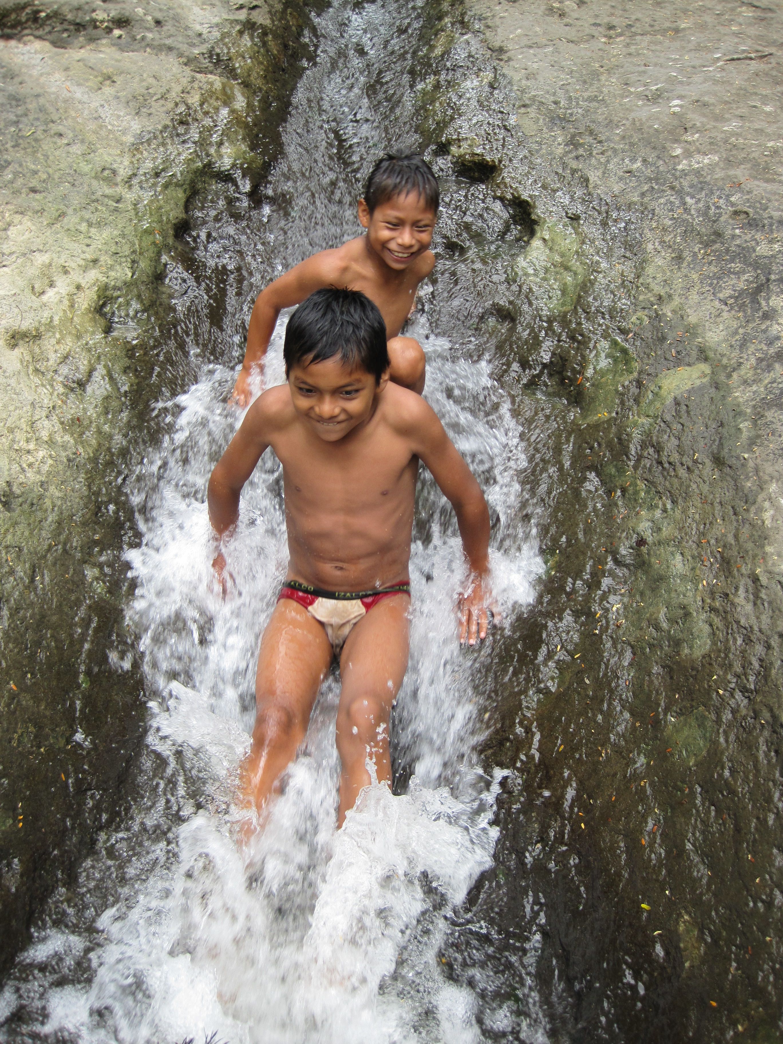 Two children playing in a water stream.