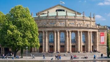 A large building with classical architecture, featuring columns, a central dome, and statues on the roof.