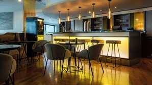 A modern bar area with a curved counter, bar stools, and pendant lighting. - elaya hotel stuttgart boeblingen (Boeblingen)