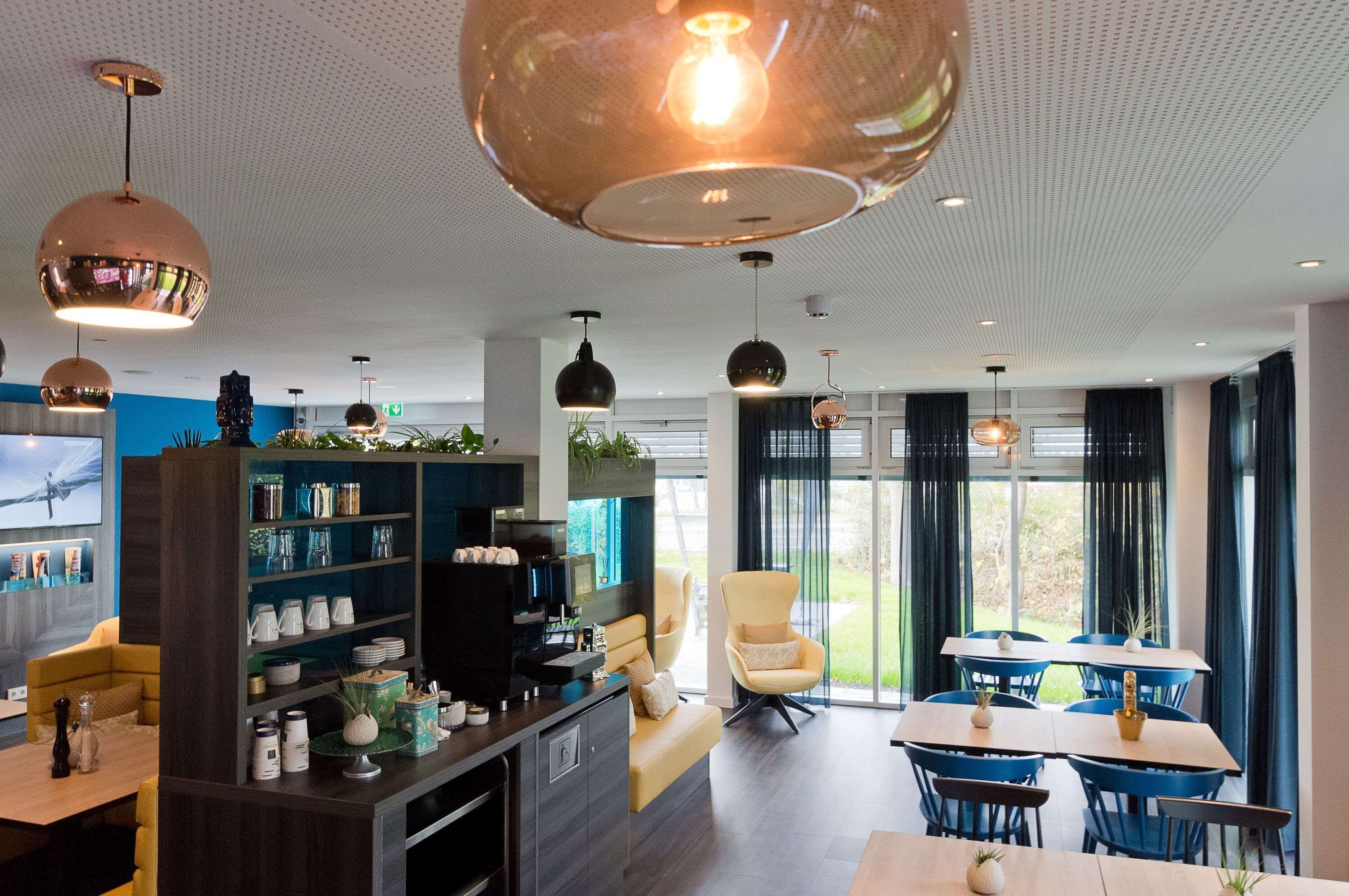 Et moderne interiør med spiseplads, opholdsstue med sofa og et køkken med hylder og hårde hvidevarer.