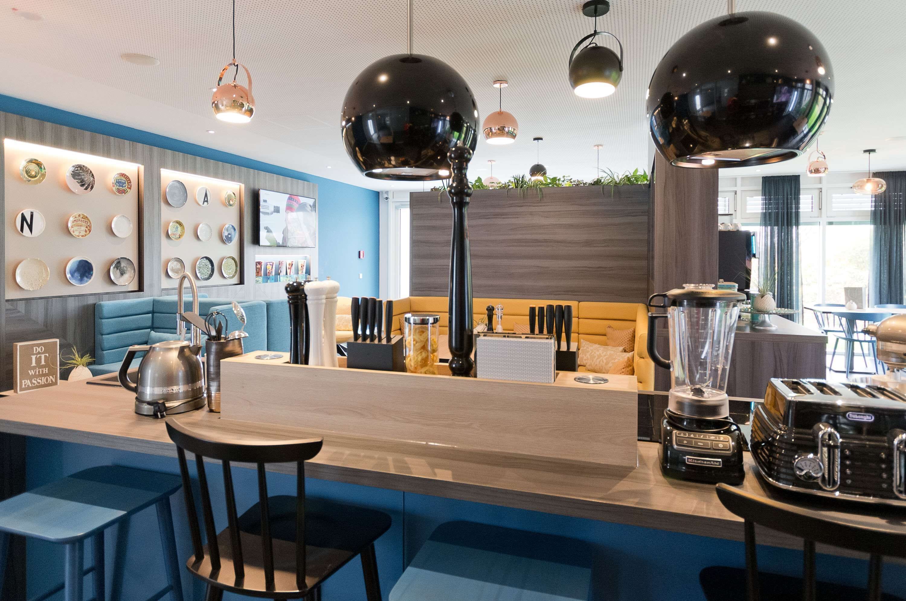A modern bar area with a wooden counter, bar stools, and a variety of kitchen appliances.