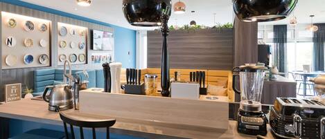 Un área de bar moderna con mostrador de madera, taburetes y una variedad de electrodomésticos de cocina.