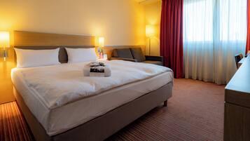 Une chambre d’hôtel avec un grand lit, deux tables de chevet, un bureau et une chaise.