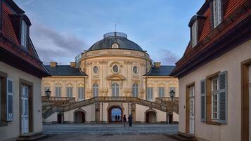Un edificio histórico con una cúpula central, arquitectura simétrica y un patio con una escalera que conduce a la entrada.