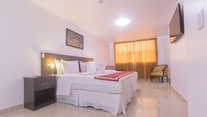 A hotel room with a bed, bedside table, and a chair. - Qallwa Pucallpa (Callería)