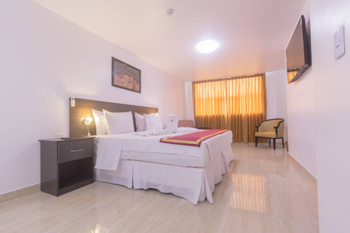 Una habitación de hotel con cama, mesita de noche y una silla.