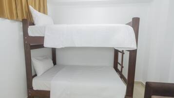 Ein Stockbett mit weißer Bettwäsche in einem Zimmer mit hellen Wänden und Holzmöbeln.