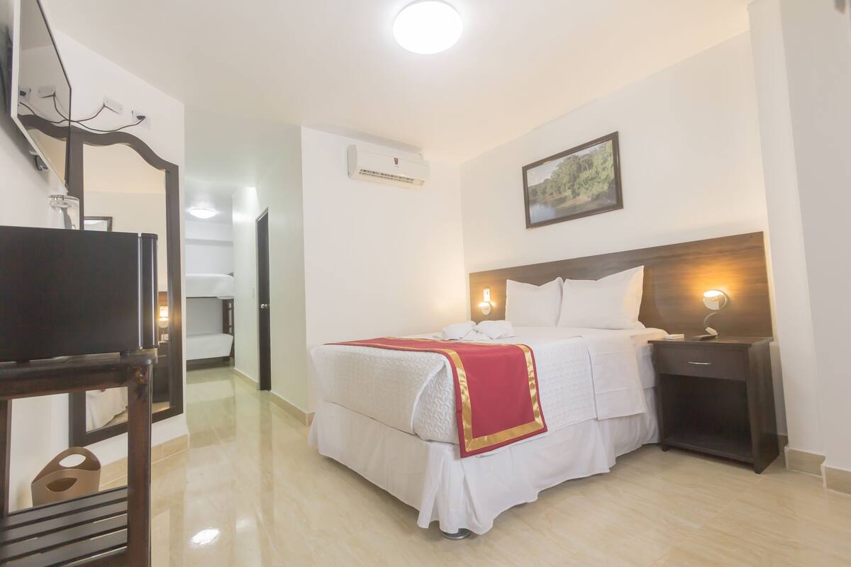 Una habitación de hotel con una cama, mesita de noche y un espejo.