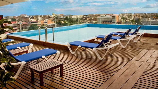 A rooftop pool area with lounge chairs and a wooden deck. - Qallwa Pucallpa (Callería)