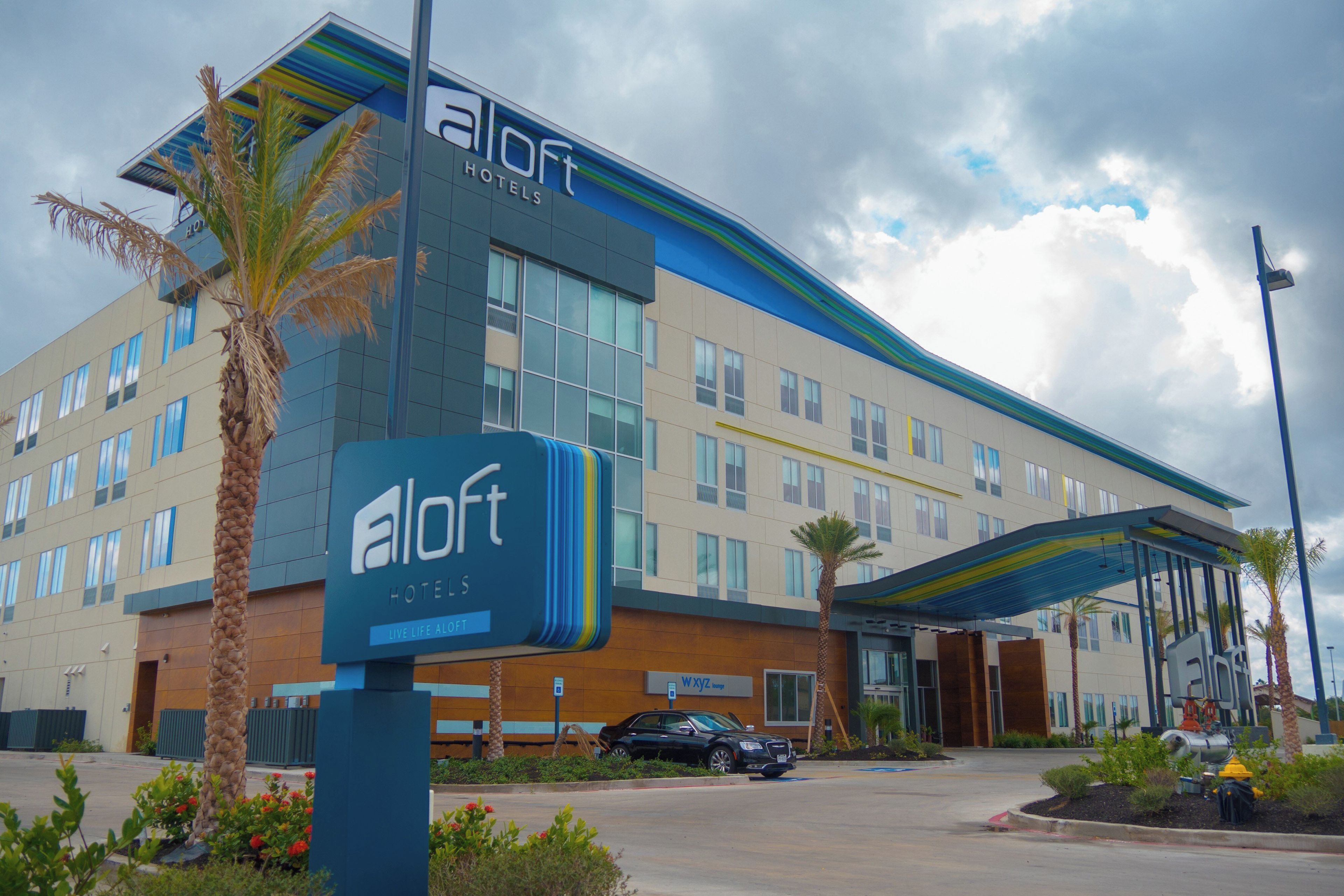 Un hôtel au design moderne, avec une enseigne « eLoft Hotels » bien visible et une entrée abritée.