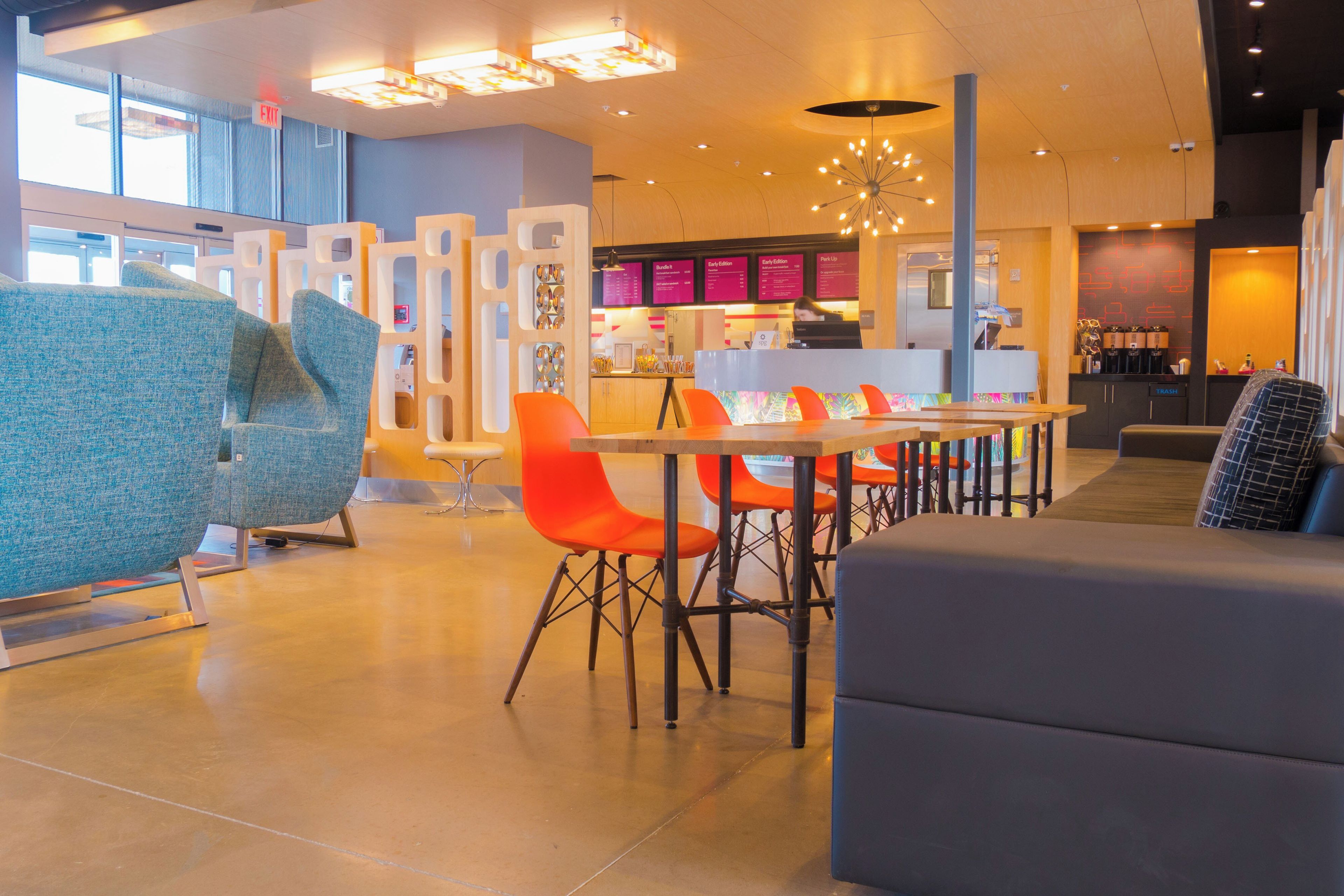 A modern interior with seating areas, a counter, and a menu board.