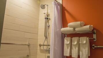 A shower area with a showerhead, curtain, and multiple towels on a rack.