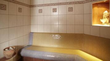 A spa room with a tiled wall, a bench, and a statue.