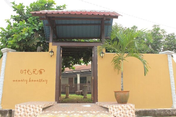 A building entrance with a sign reading "memory homestay" and a large potted plant.