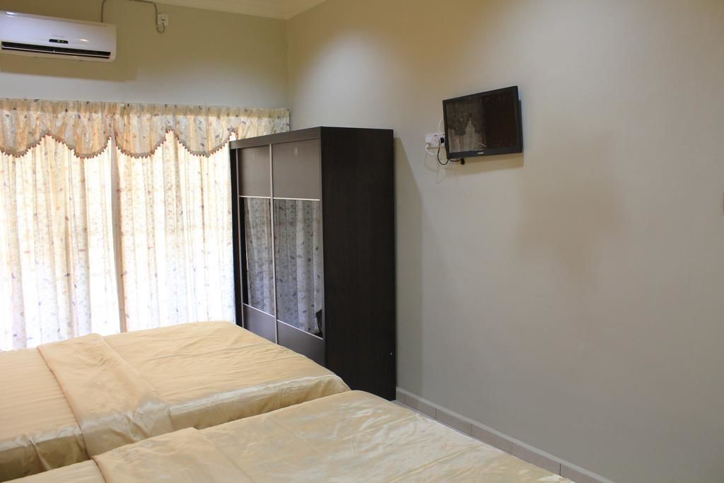 A bedroom with two beds, a wardrobe, an air conditioning unit, and a wall-mounted TV.