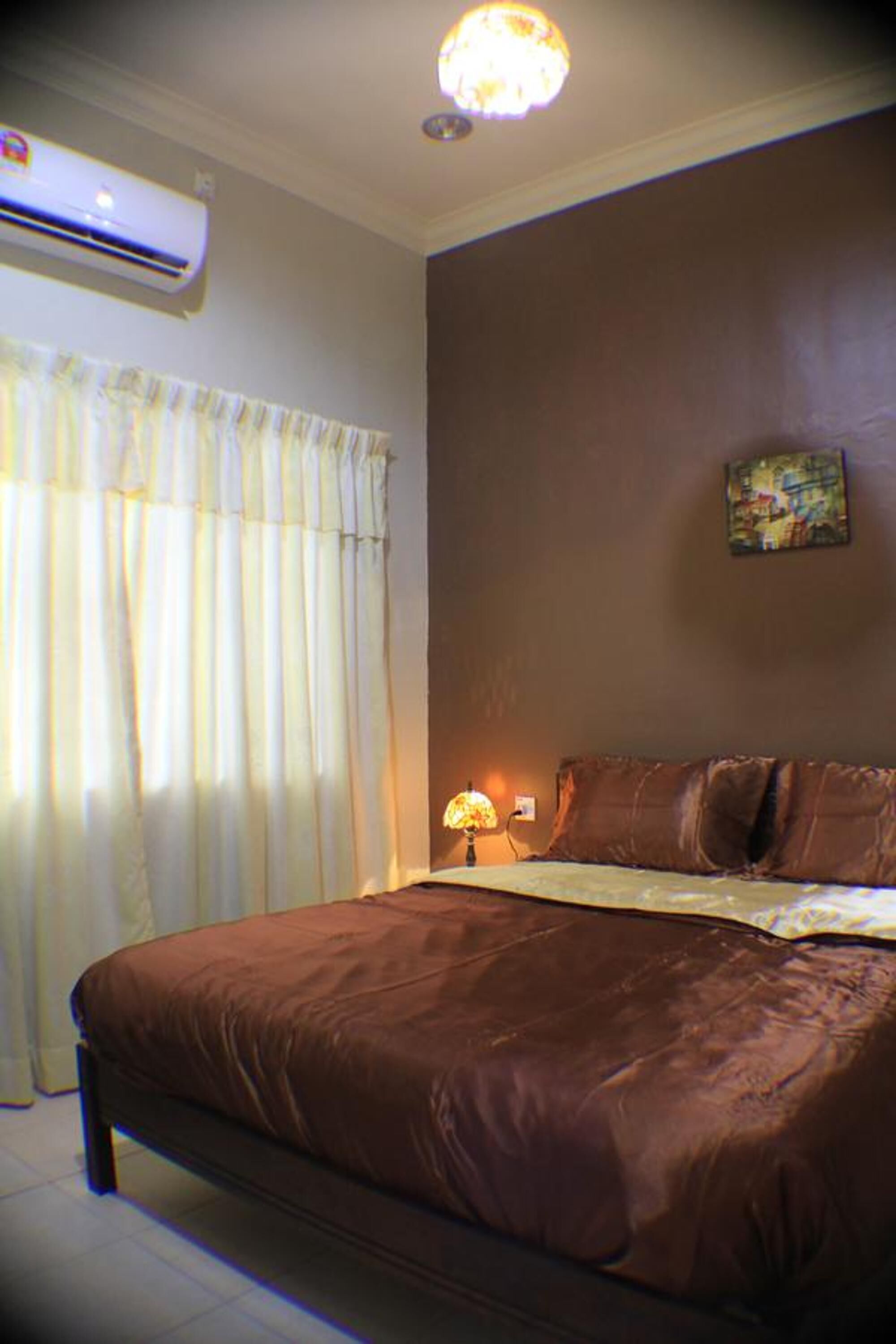 Un dormitorio con una cama grande, un aire acondicionado, una lámpara y un cuadro en la pared.