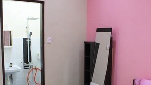A bedroom with a pink bedspread, a black wardrobe, and a mirror.